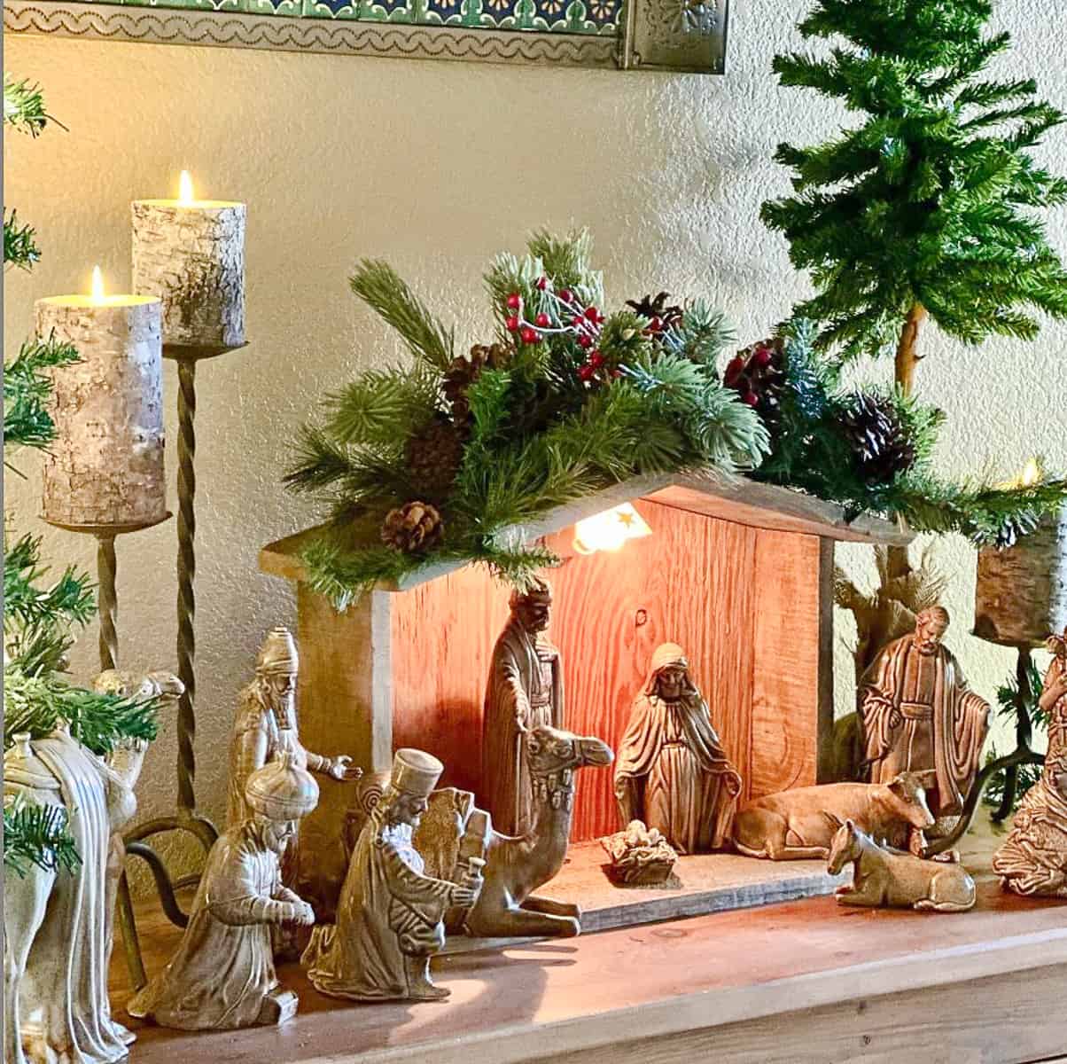 nativity display scene on a table surrounded with faux greenery