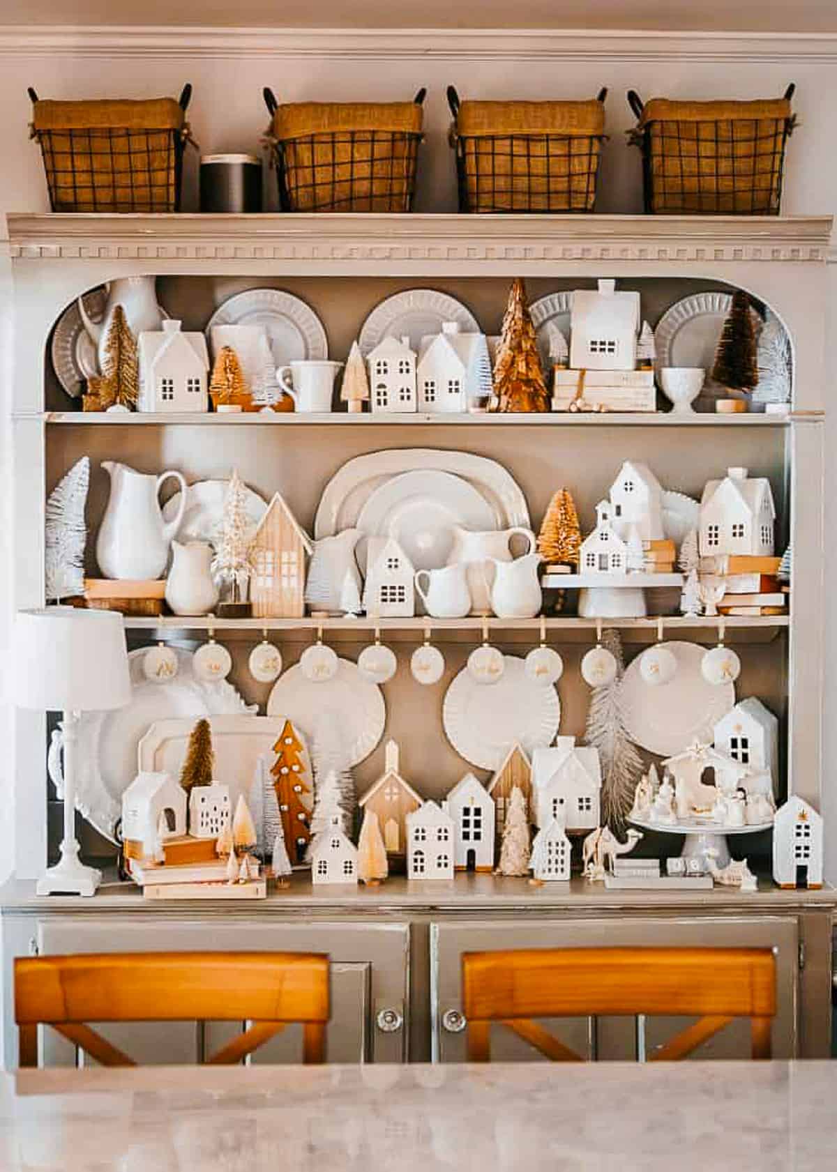 small nativity scene in a large hutch filled with white stoneware and dishes