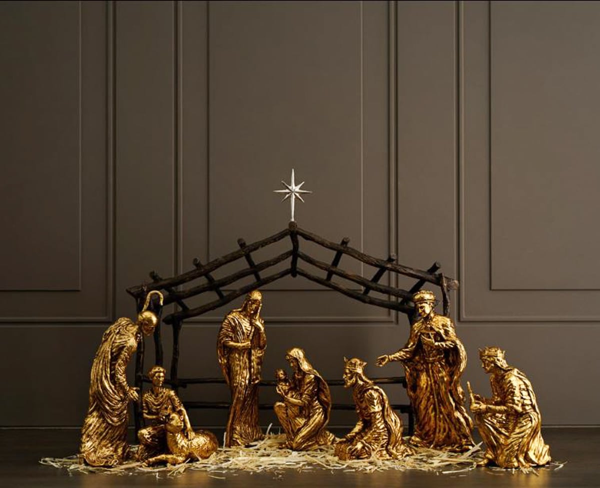 gold nativity scene in a creche against a wall painted dark gray
