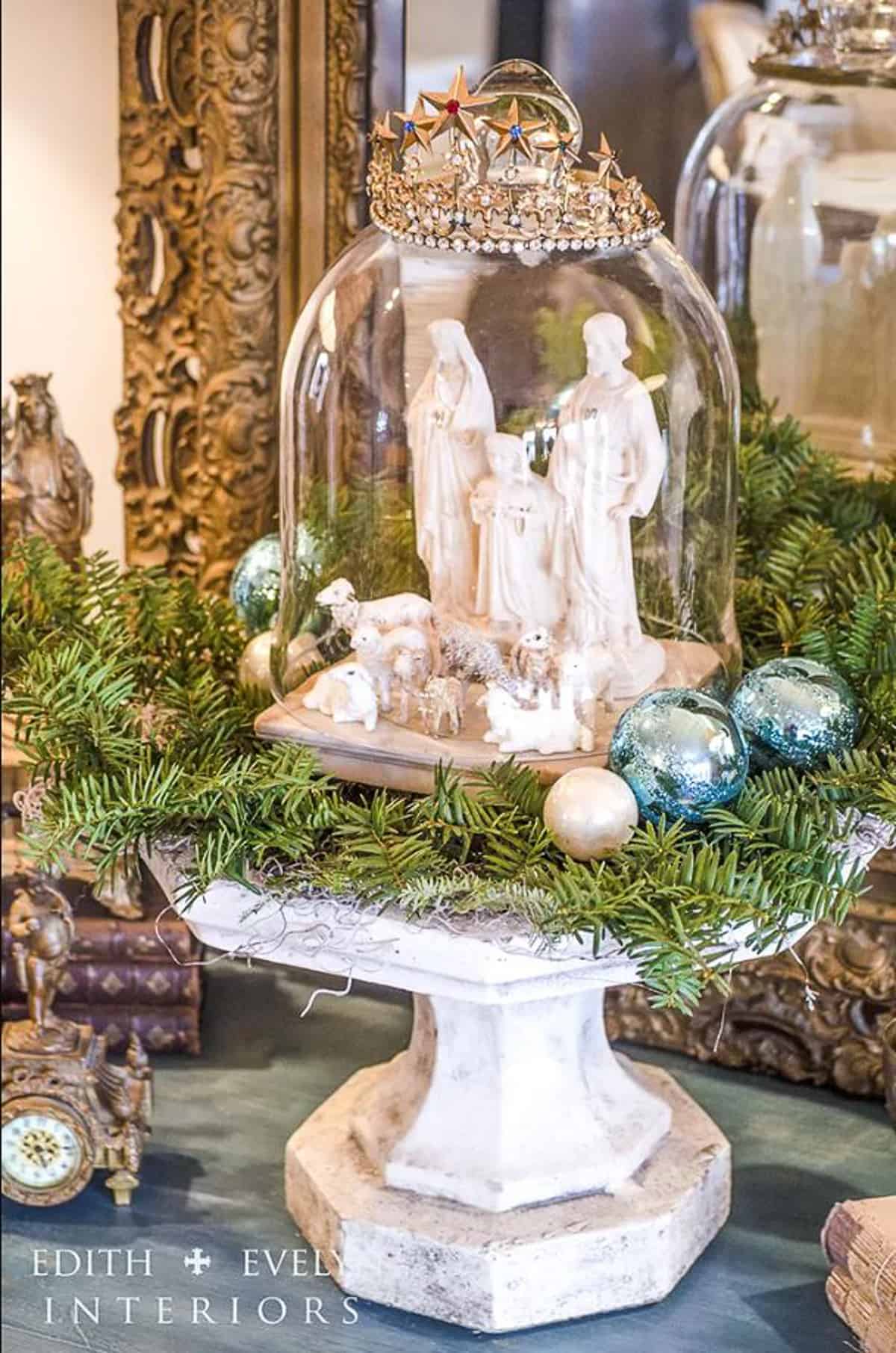 nativity set under a glass cloche on a cake stand