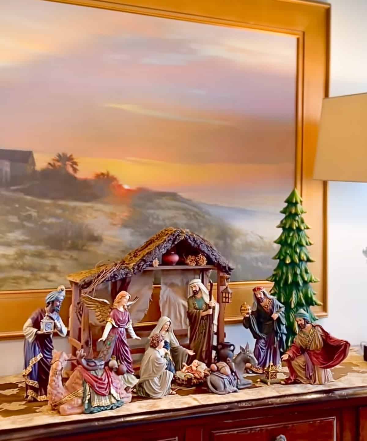 nativity scene on sideboard with artwork hanging on wall above