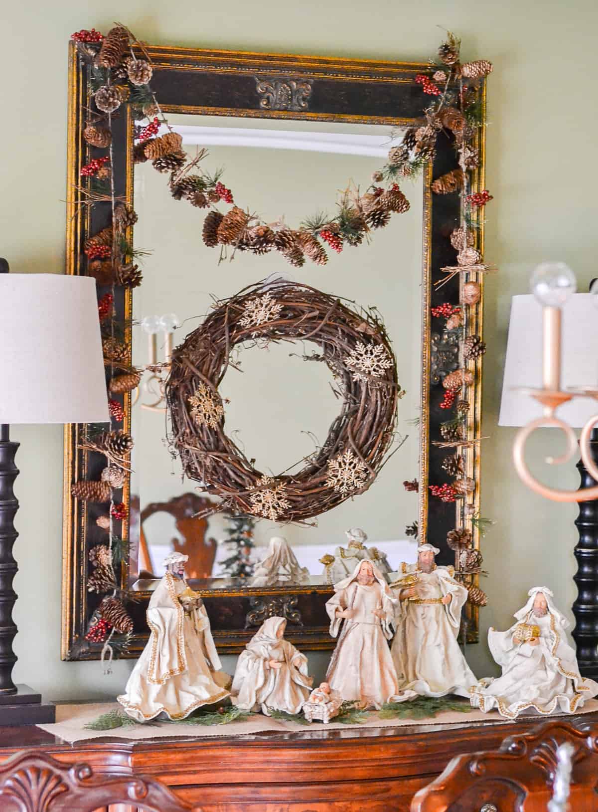 neutral colored nativity scene display on a sideboard with a mirror hanging above