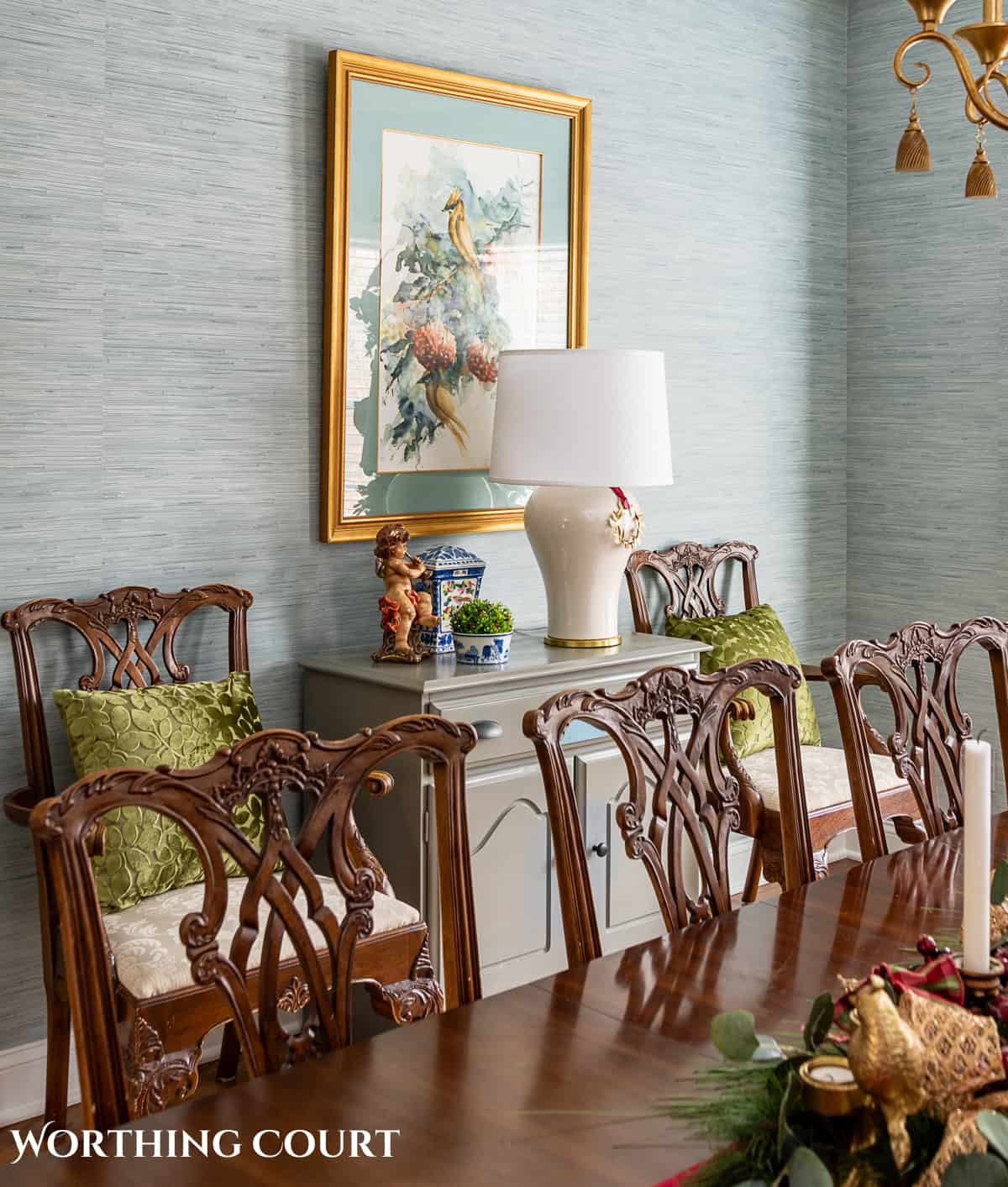 Dining room with traditional wood furniture decorated for Christmas with sage green, burgundy, and gold decorations.