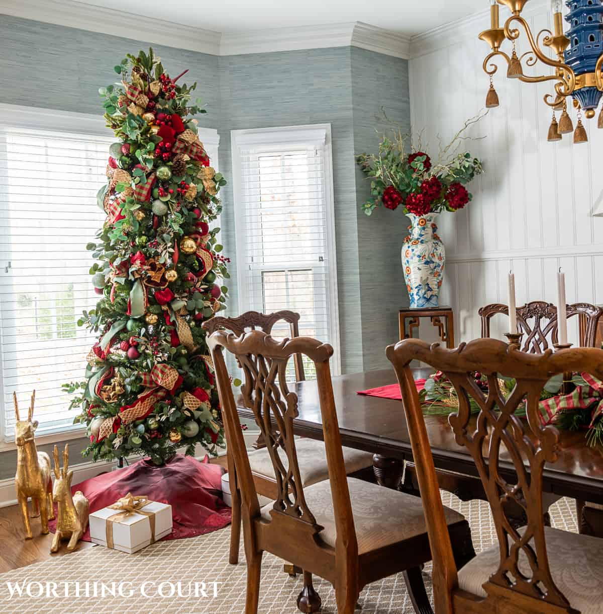 Dining room with traditional wood furniture decorated for Christmas with sage green, burgundy, and gold decorations.