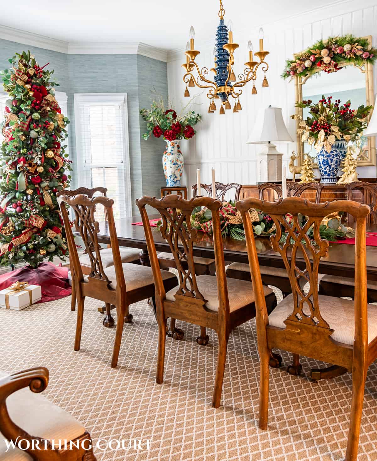 Dining room with traditional wood furniture decorated for Christmas with sage green, burgundy, and gold decorations.