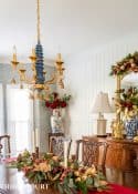 Dining room with traditional wood furniture decorated for Christmas with sage green, burgundy, and gold decorations.
