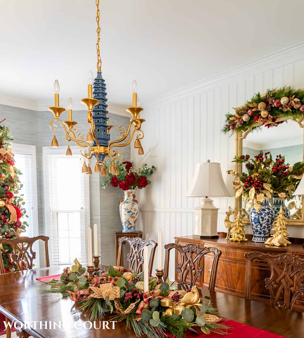 Dining room with traditional wood furniture decorated for Christmas with sage green, burgundy, and gold decorations.