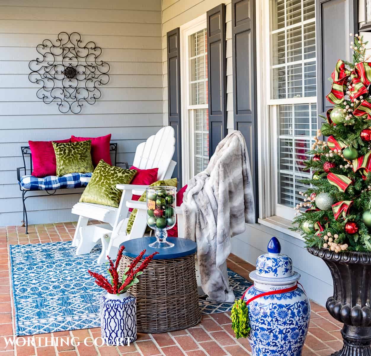 two white adirondack chairs on a front porch decorated with red and green for Christmas