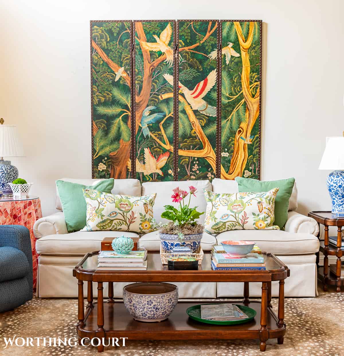 tan couch against a wall with a decorative screen hung above it and a decorated coffee table in front