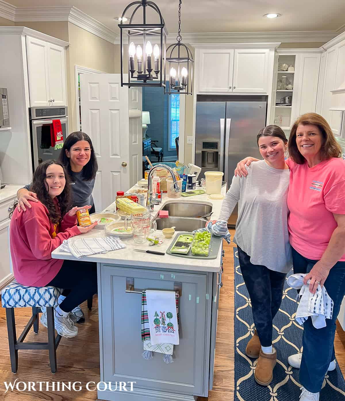 4 women standing around an island in a kitchen with white cabinets