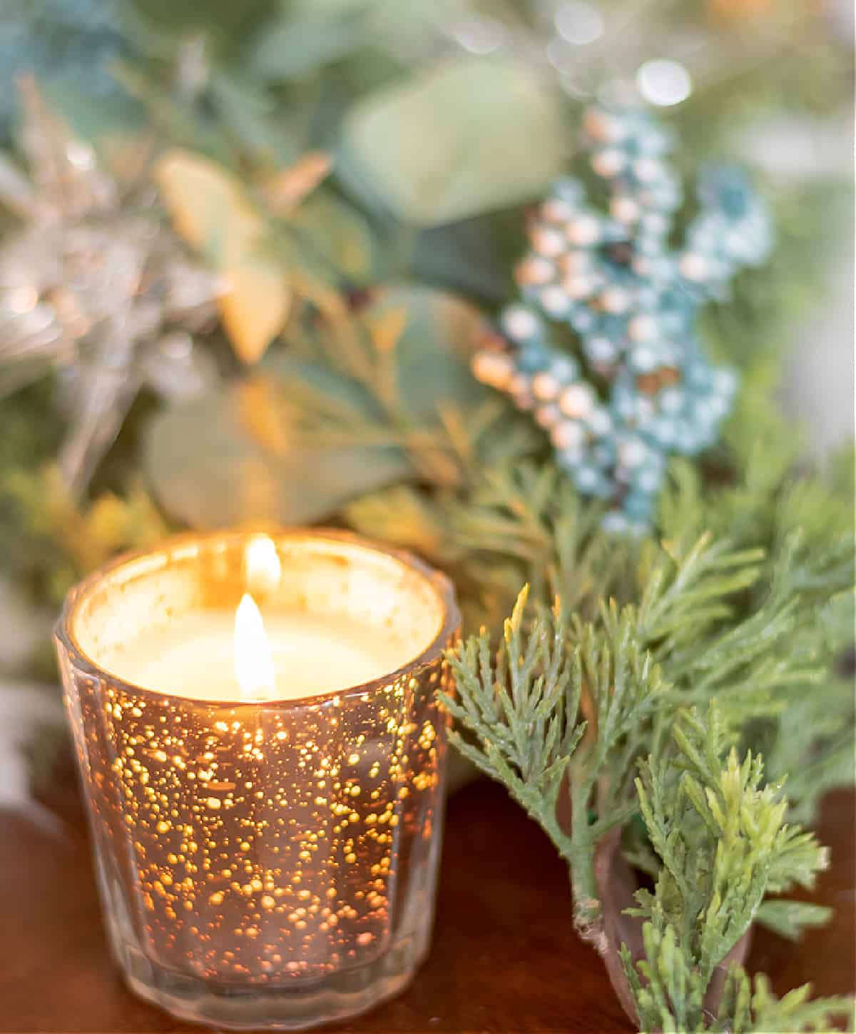 flickering candle in a mercury glass holder amongst winter evergreens