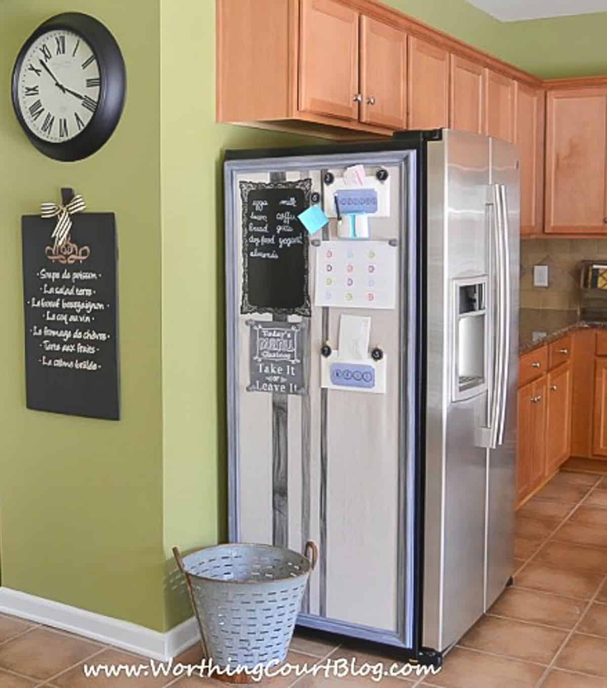 side of refrigerator with diy bulletin board in a kitchen with green walls and wood cabinets