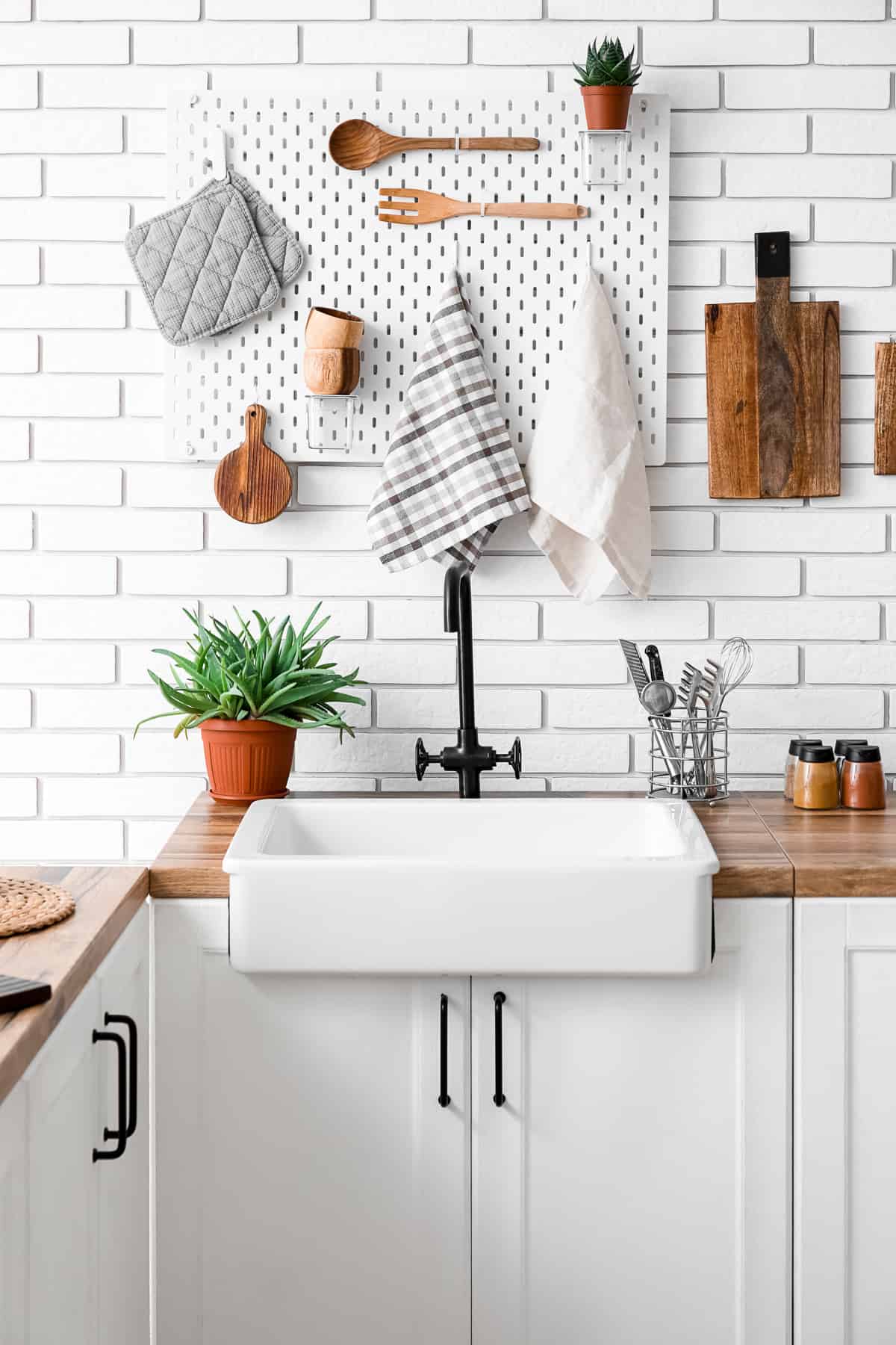 pegboard on a kitchen wall above a white farmhouse sink and cabinets