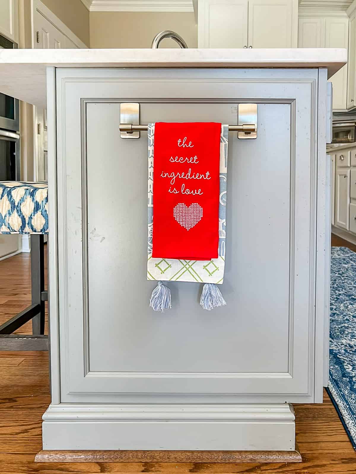 end of a gray kitchen cabinet with kitchen towels hanging on a towel bar