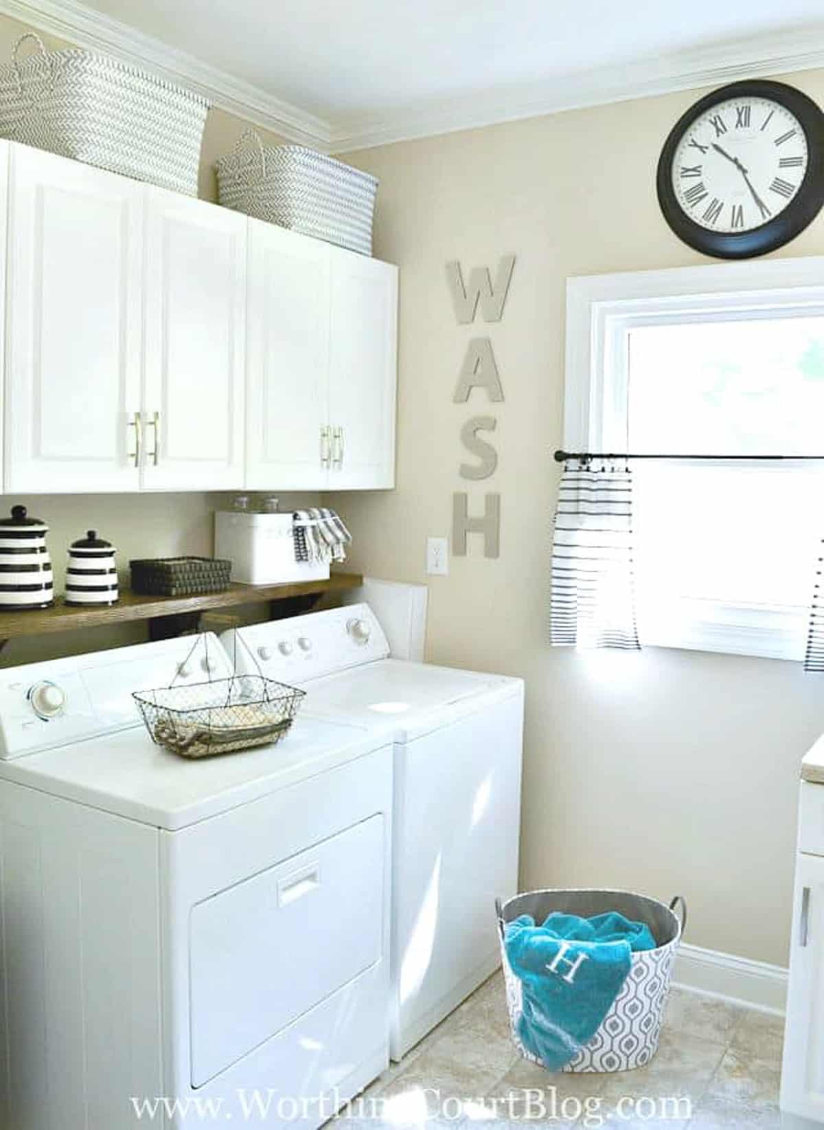 decorated laundry room with top loader washer and dryer with white cabinets above