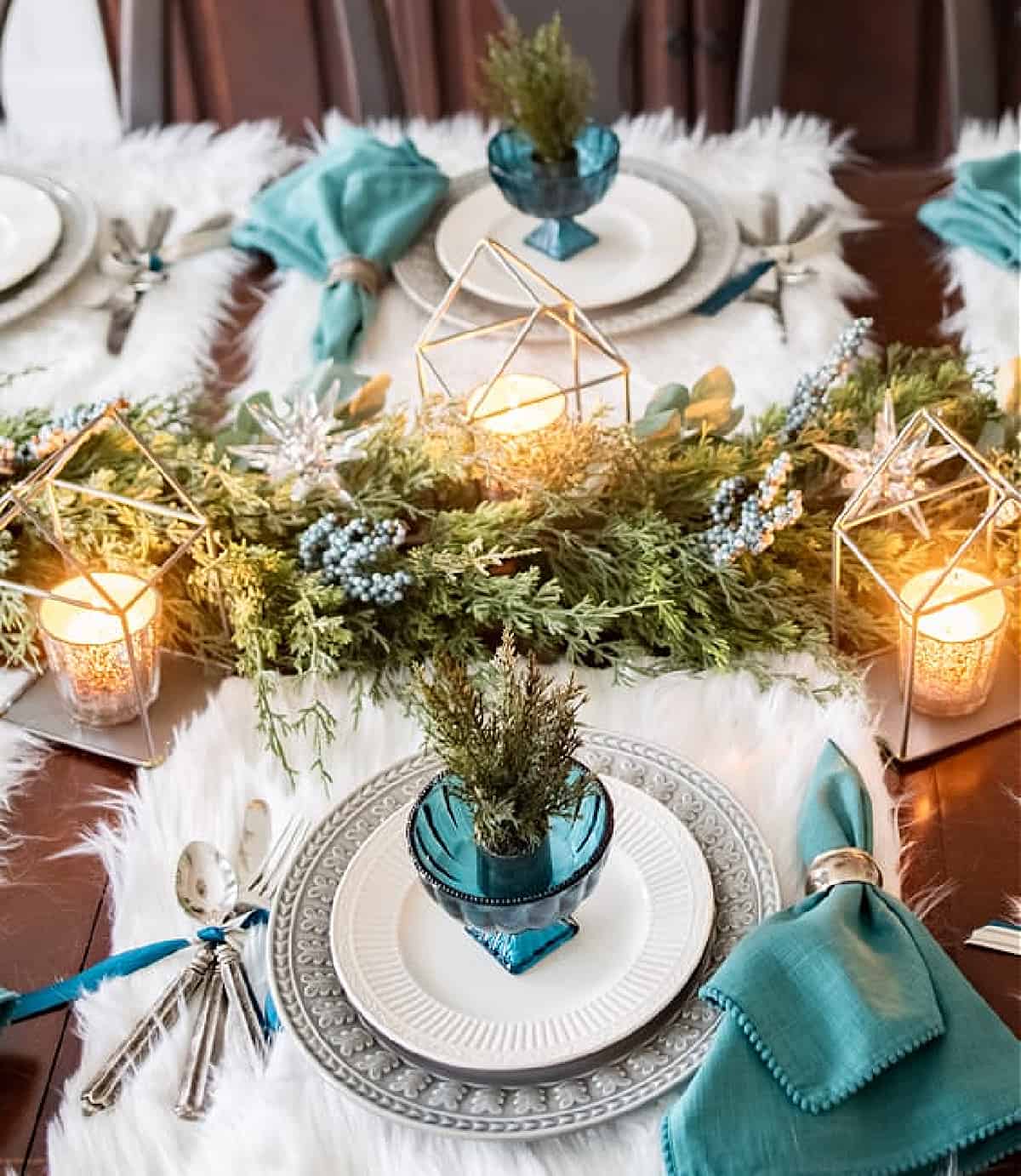 table set for winter with teal, white and gray dishes and faux fur placemats