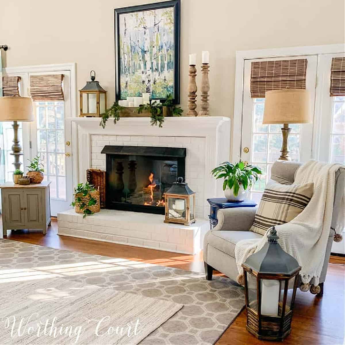white brick fireplace decorated for winter in a living room with neutral furnishings