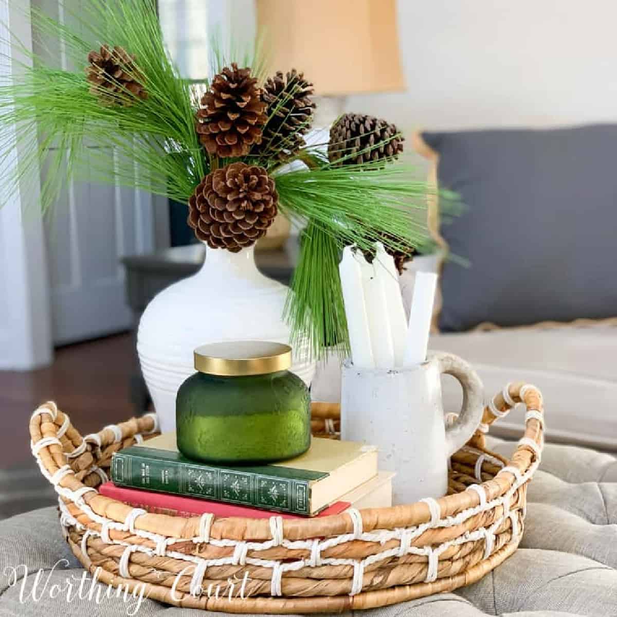 winter vignette in a wicker tray usingh greena nd white, candles and pinecones