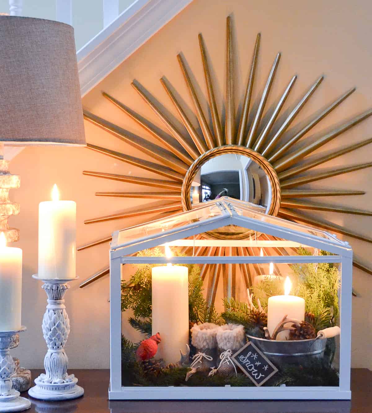 terrarium on a chest filled with small winter accessories and candles