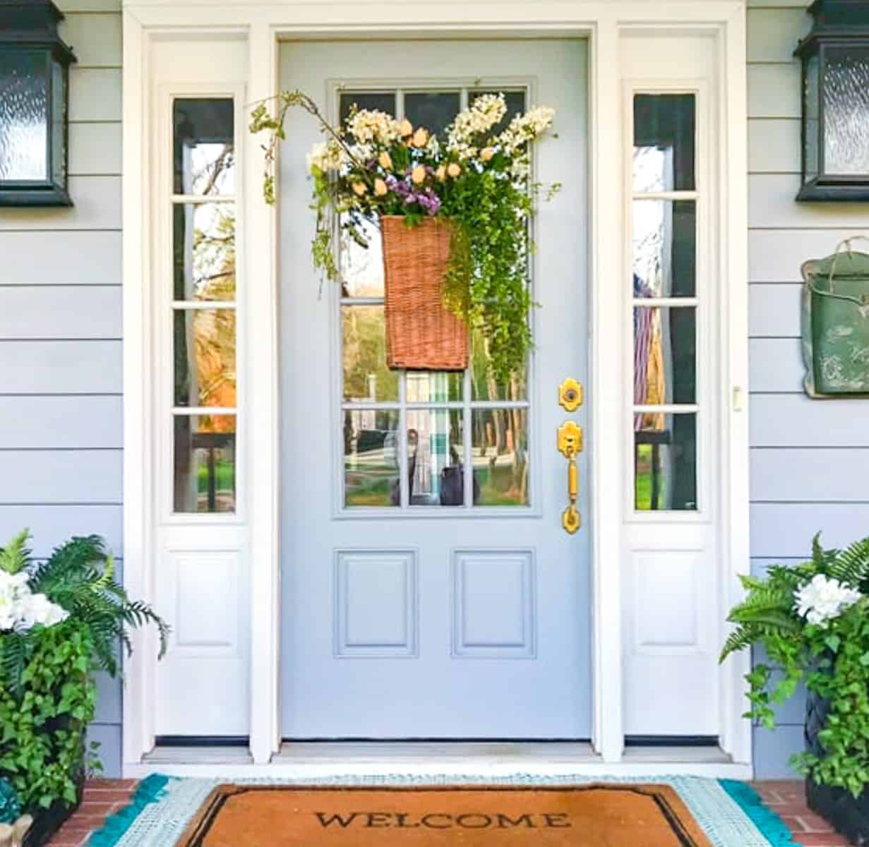 hanging basket on a gray front door filled with white and green flowers for spring