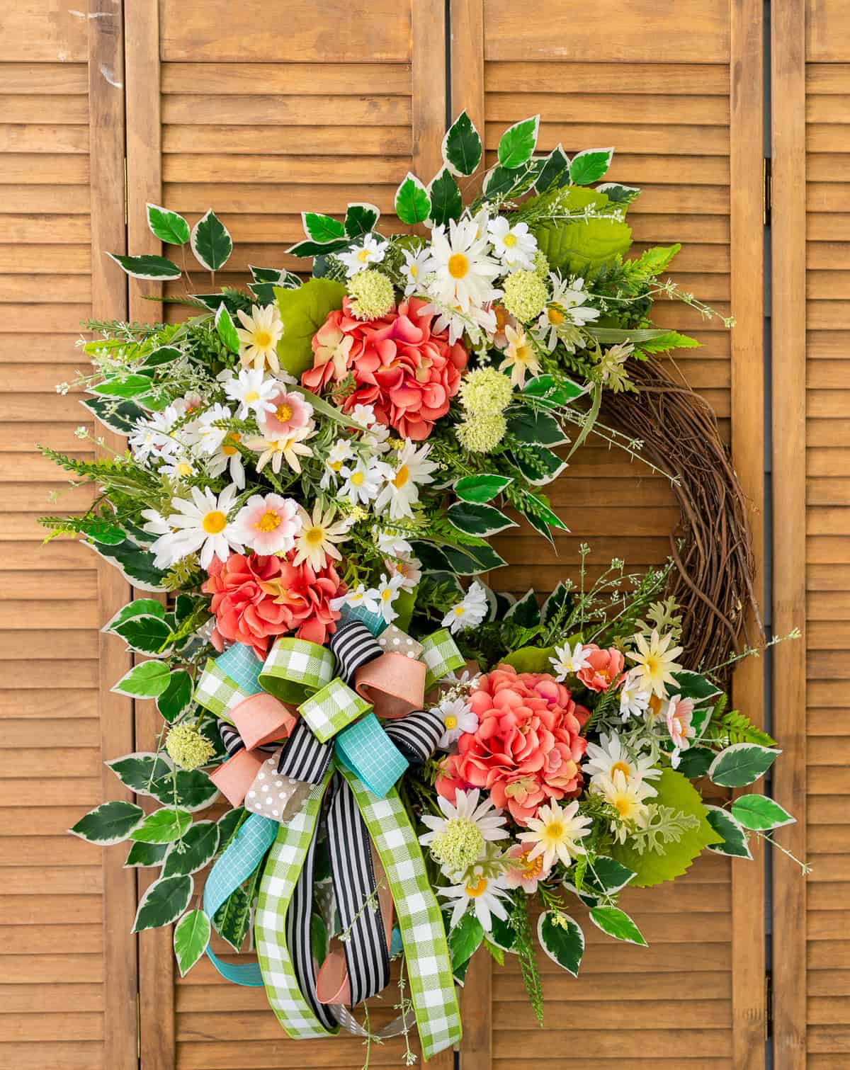 assortment of brightly colored flowers and ribbon on a grapevine wreath for spring