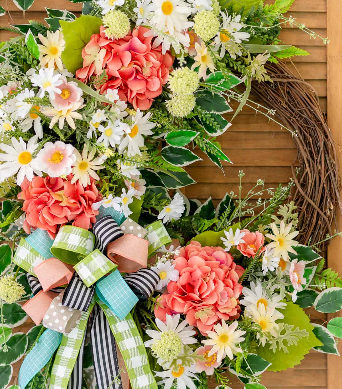 assortment of brightly colored flowers and ribbon on a grapevine wreath for spring