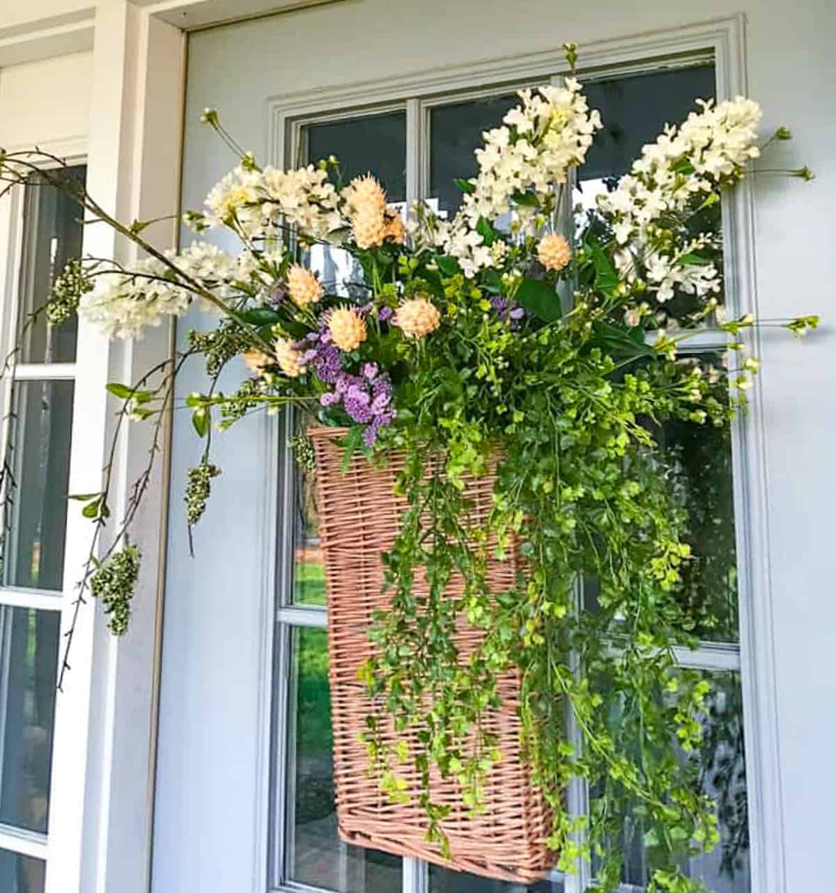 hanging basket on a gray front door filled with white and green flowers for spring