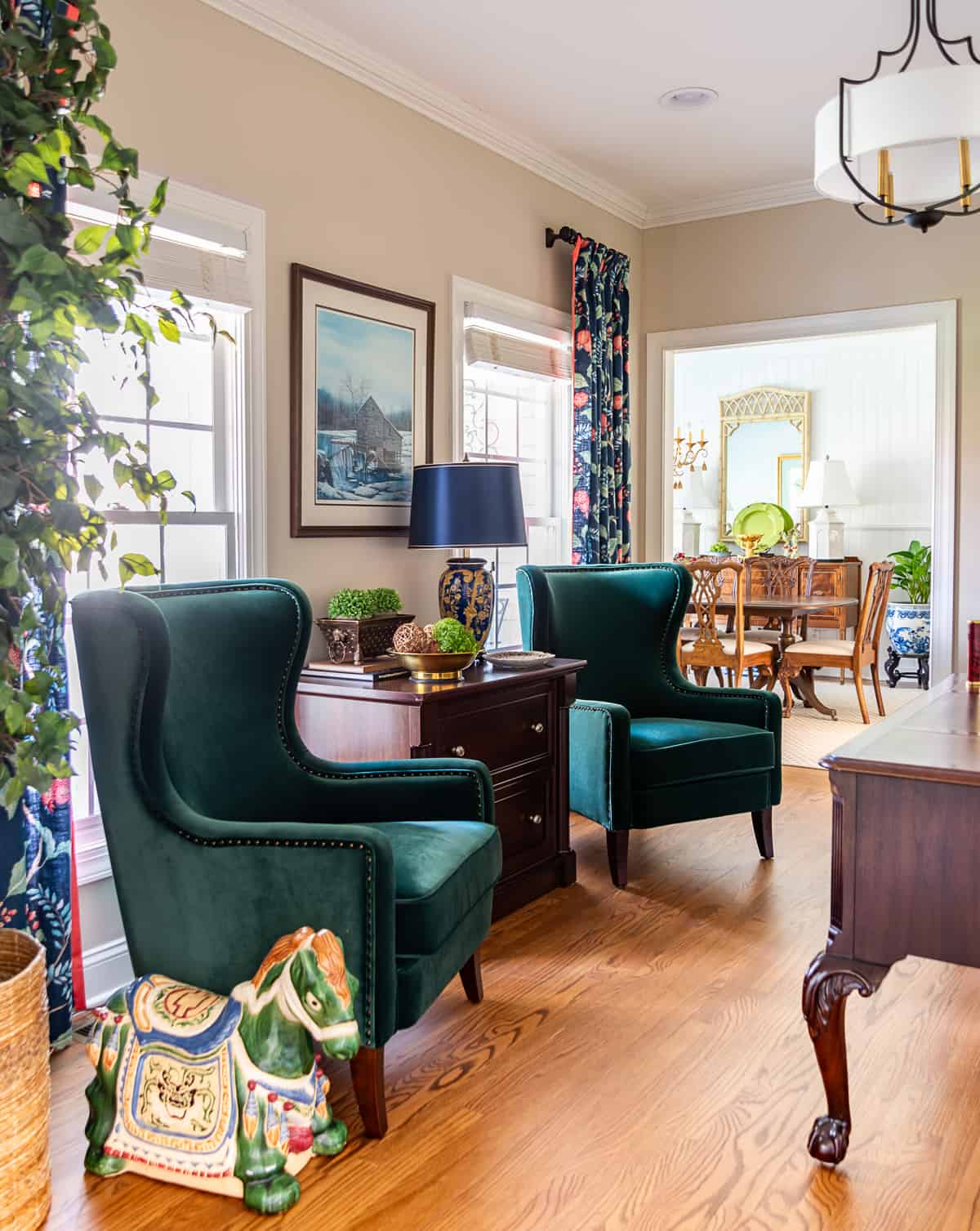 Pair of trending green velvet arm chairs in front of two windows in a home office