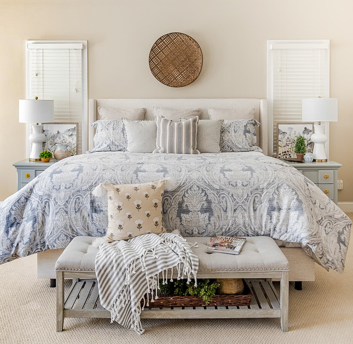 King size bed with neutral bedding flanked by gray nightstands with white lamps