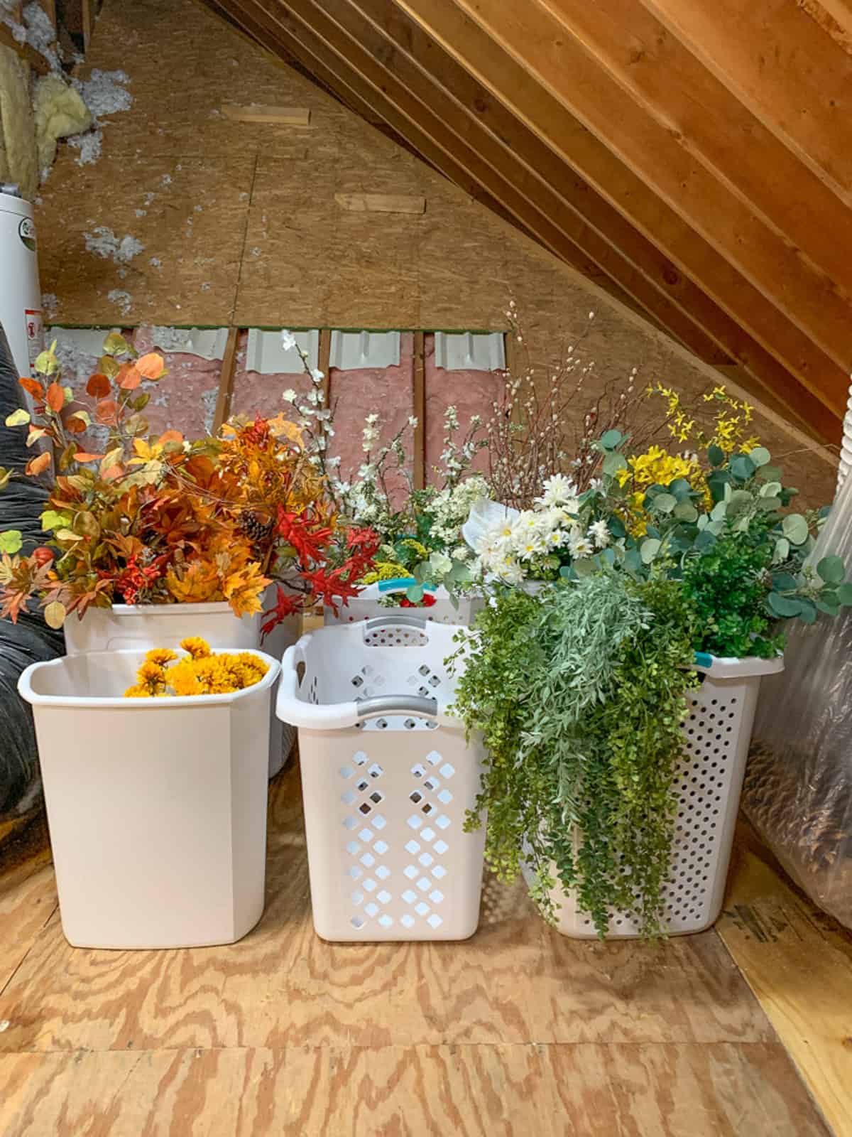 artificial flowers stored in tall laundry hampers in an attic