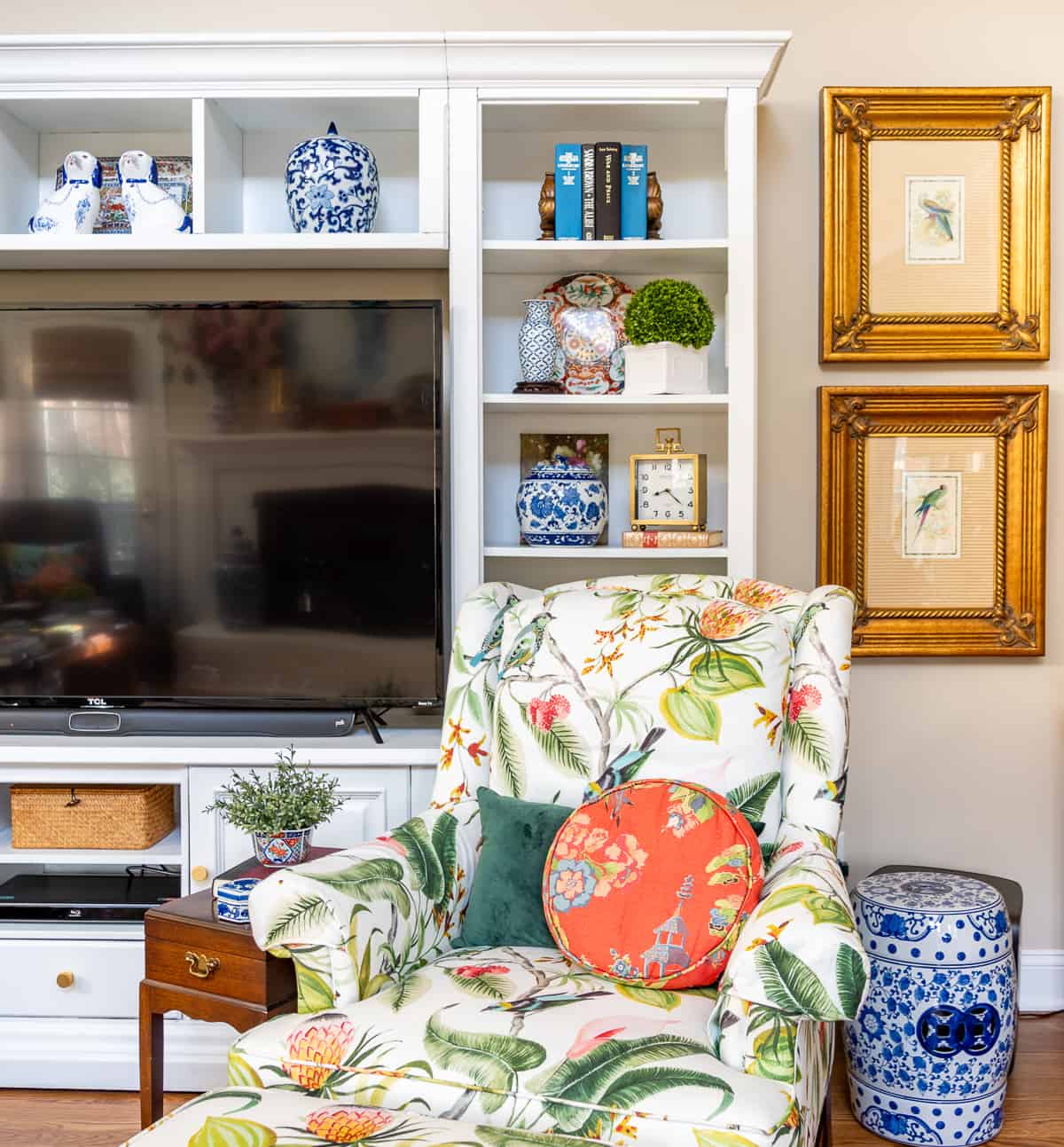 living room decorated for spring with colorful accessories in a white entertainment center with two colorful chairs in front