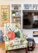 living room decorated for spring with colorful accessories in a white entertainment center with two colorful chairs in front