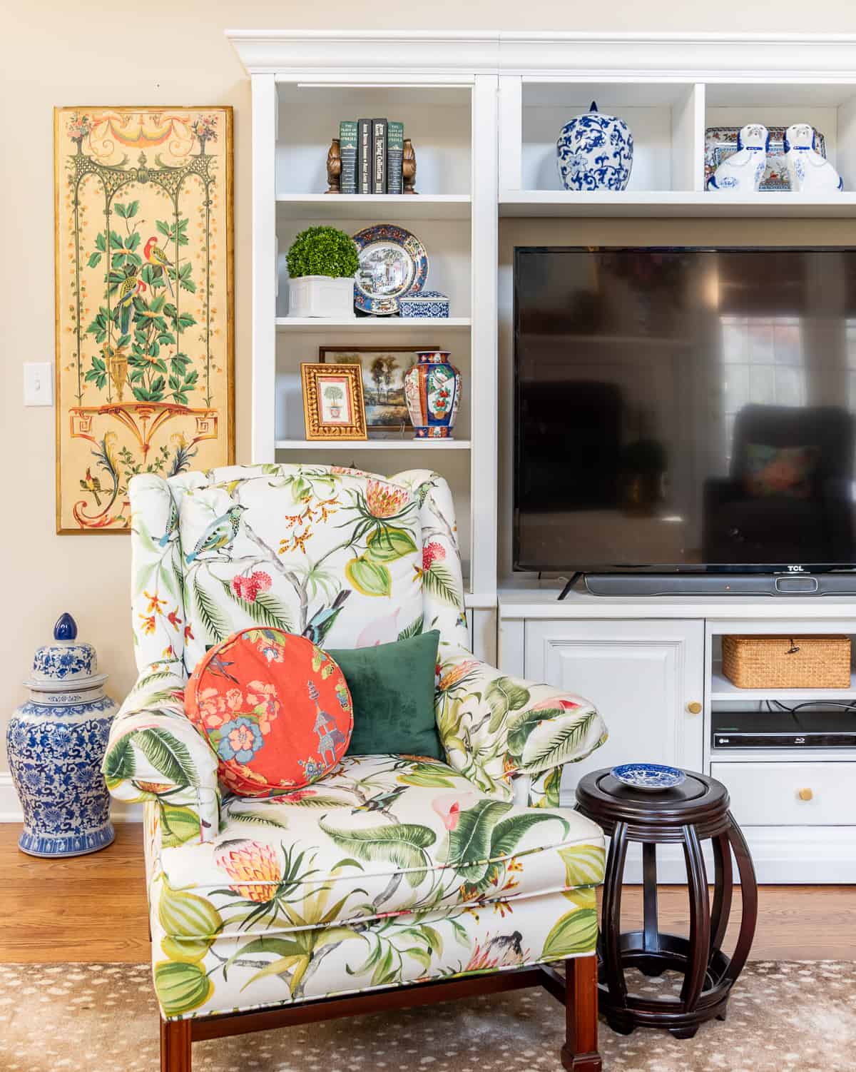 living room decorated for spring with colorful accessories in a white entertainment center with two colorful chairs in front