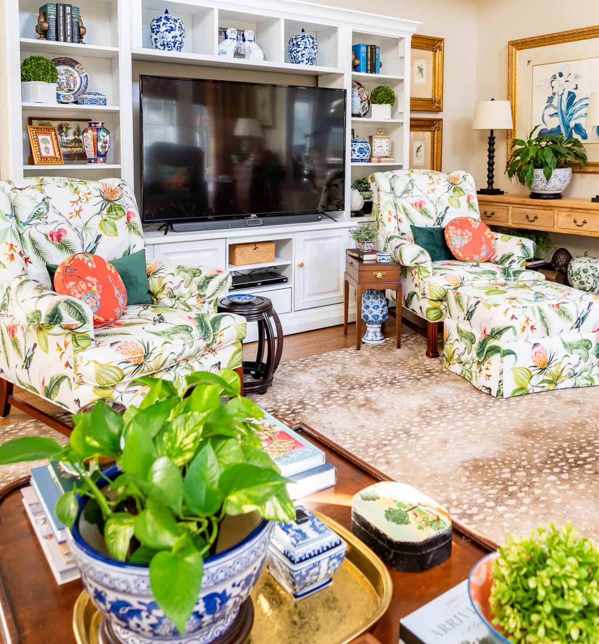 living room decorated for spring with colorful accessories in a white entertainment center with two colorful chairs in front