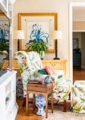 living room decorated for spring with colorful accessories in a white entertainment center with two colorful chairs in front