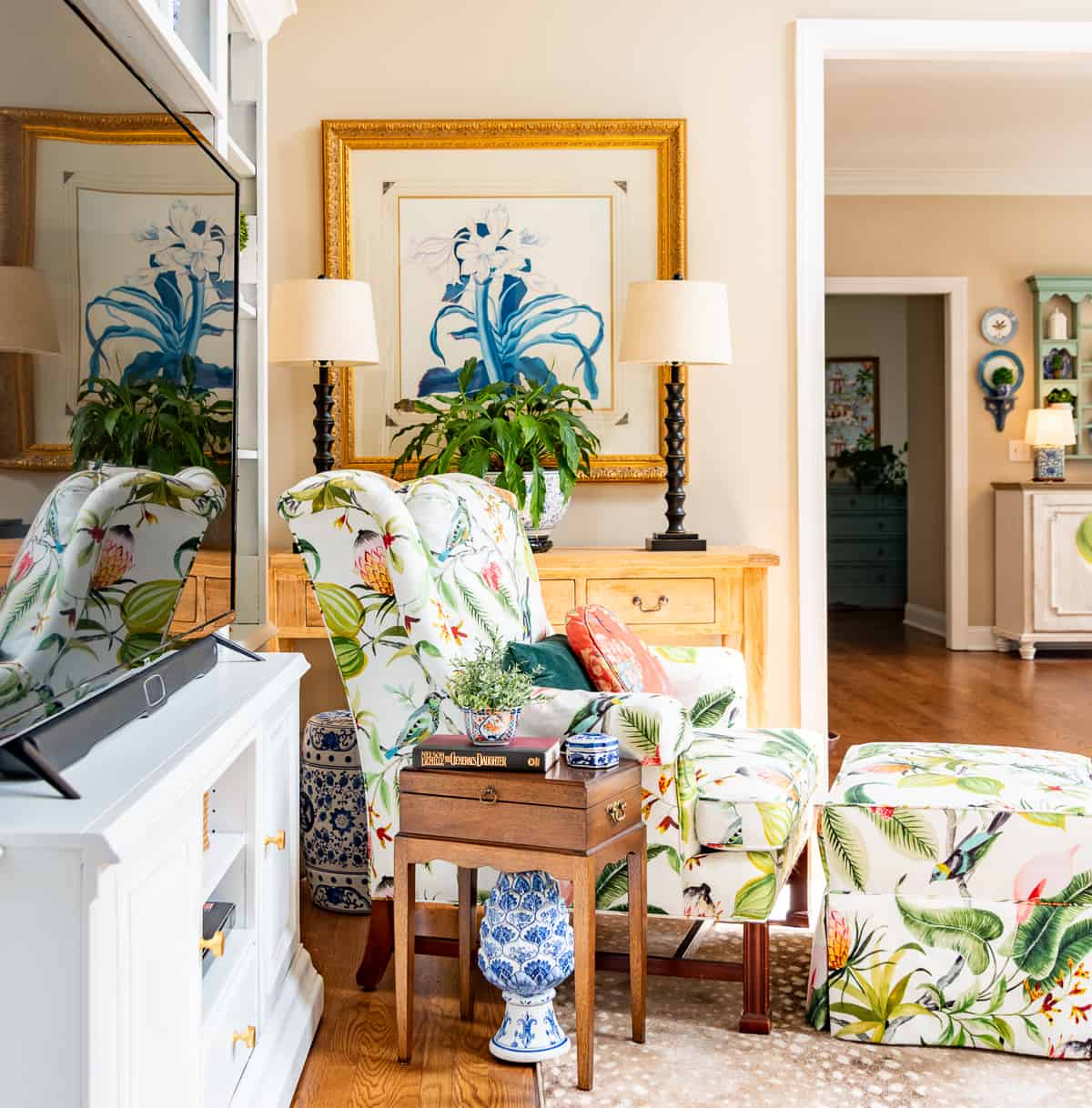 living room decorated for spring with colorful accessories in a white entertainment center with two colorful chairs in front