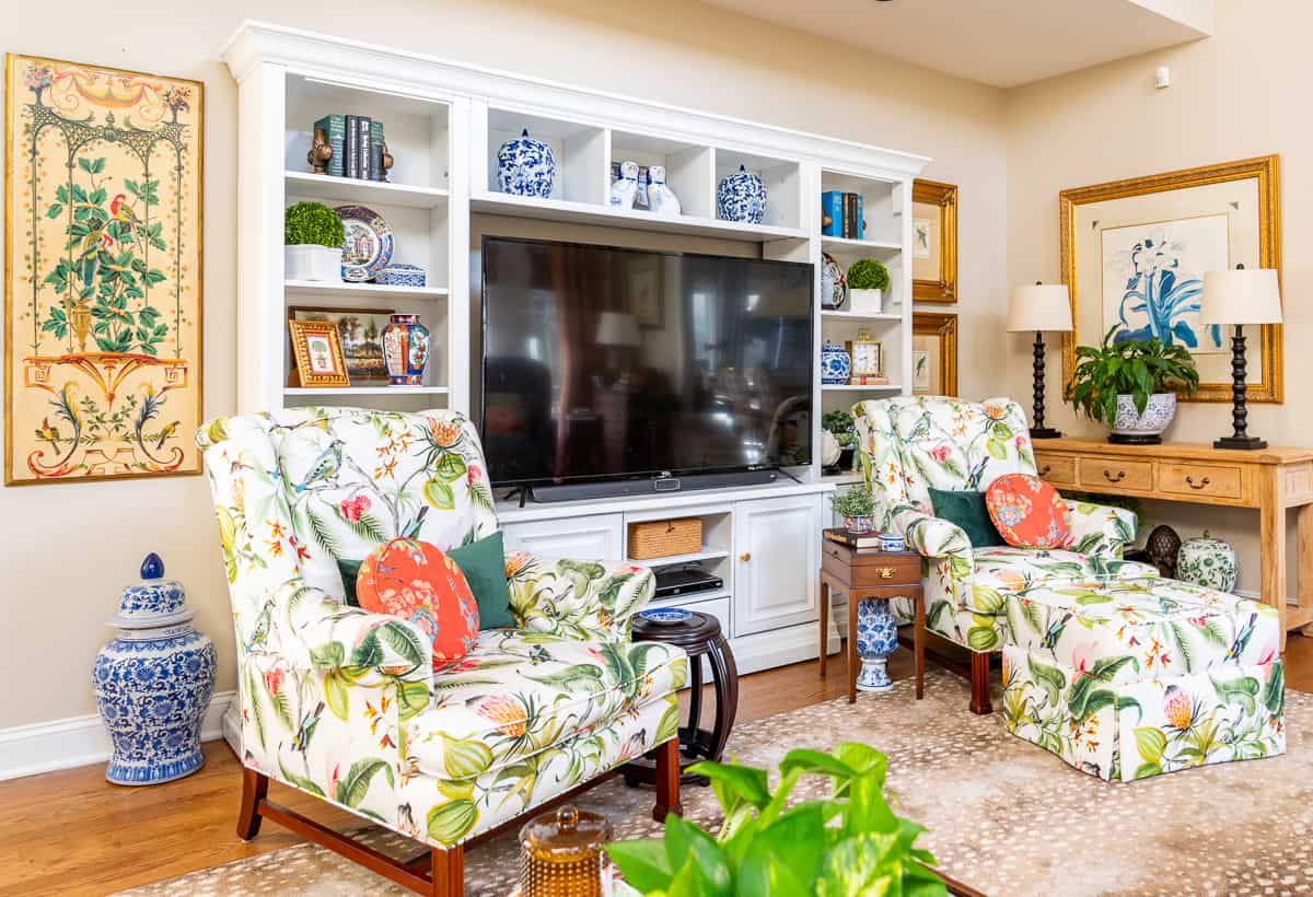 living room decorated for spring with colorful accessories in a white entertainment center with two colorful chairs in front