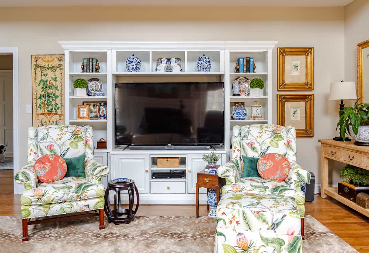 living room decorated for spring with colorful accessories in a white entertainment center with two colorful chairs in front