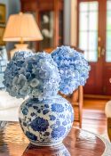 blue hydrangeas in a blue and white vase on a coffee table in a living room