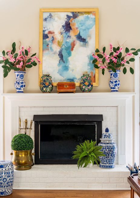 white brick fireplace with the mantel and hearth decorated with colorful accessories and abstract art