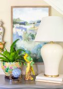off white lamp and colorful accessories on top of a small gray chest