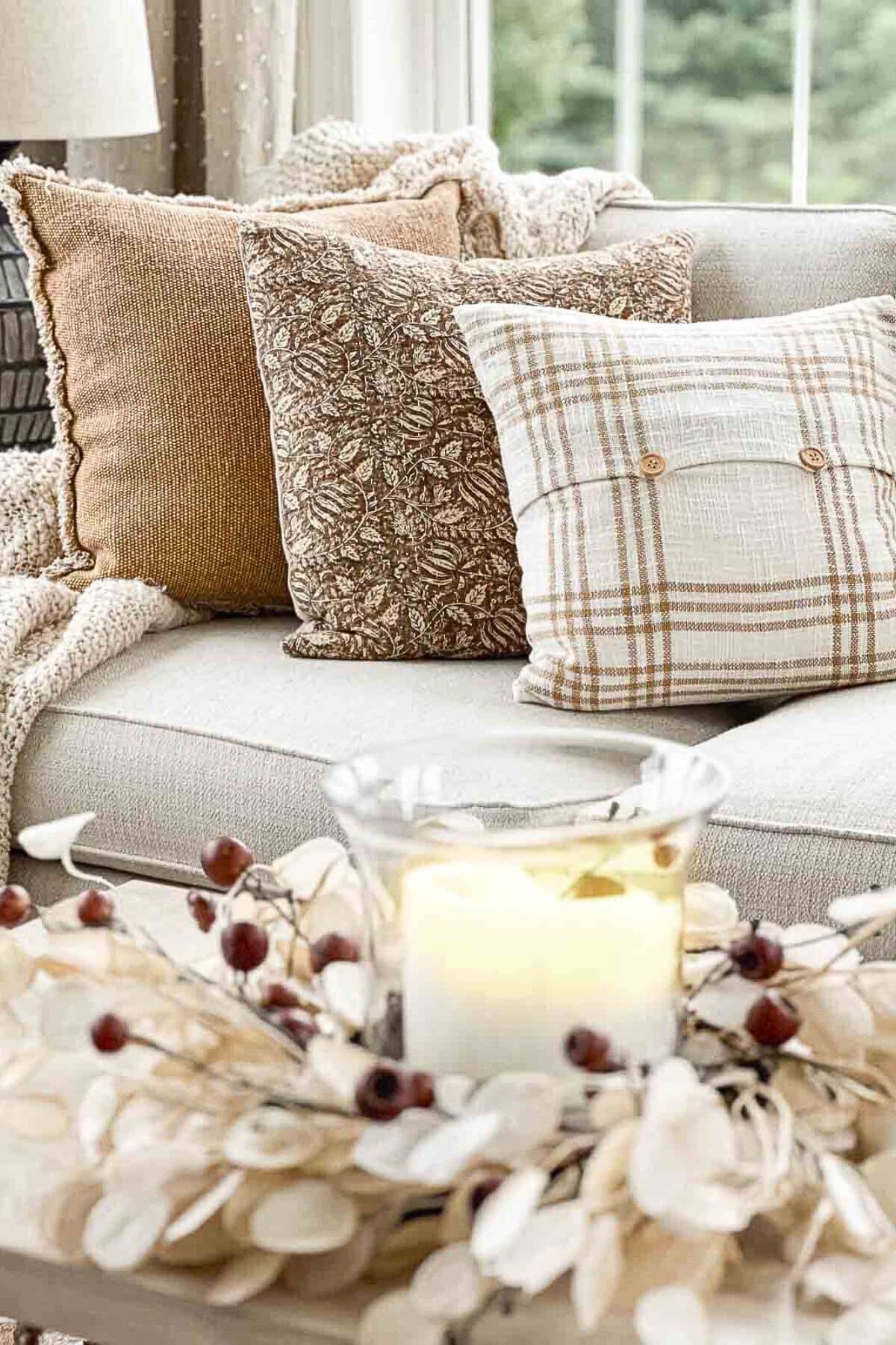 3 neutral pillows with different patterns lined up on a beige sofa