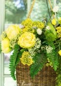 yellow flowers and greenery in a wicker basket hanging on the front door