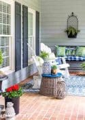 blue and green summer decor on a front porch with white chairs and a brick floor