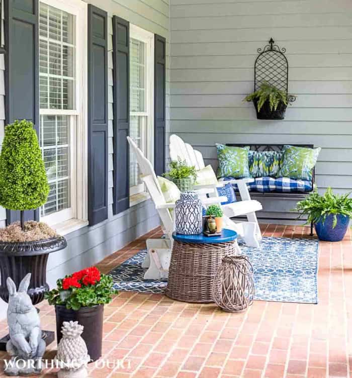 blue and green summer decor on a front porch with white chairs and a brick floor