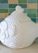 white fish shaped cookie jar in front of blue and aqua glass tile backsplash