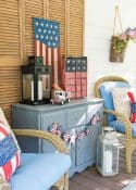 July 4th decorations on a back porch with blue arm chairs flanking a gray chest