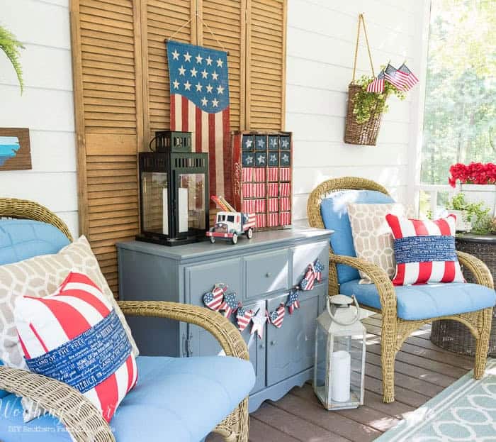 July 4th decorations on a back porch with blue arm chairs flanking a gray chest