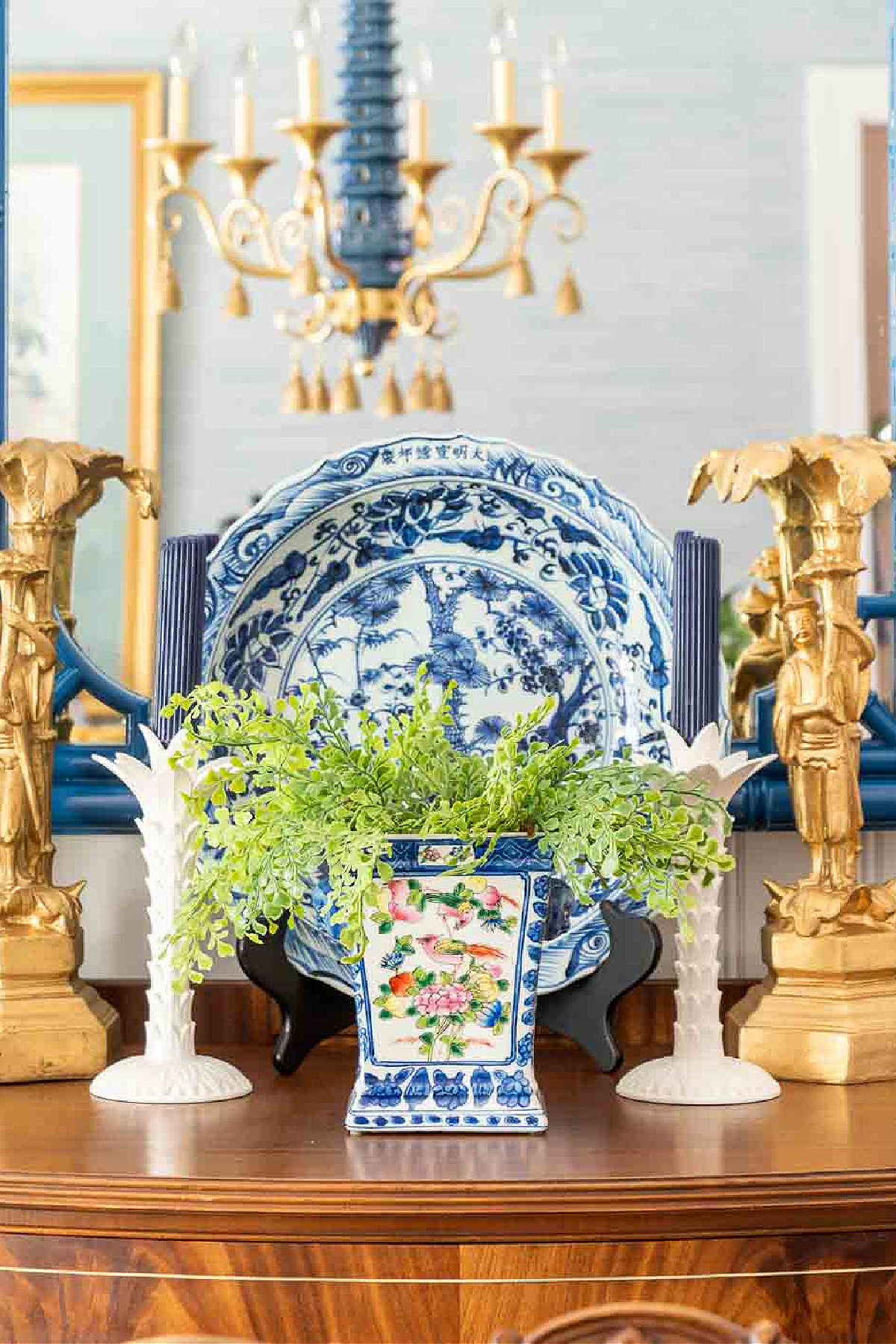 closeup of a vignette on a sideboard in front of a mirror containing blue and white chinoiserie decor