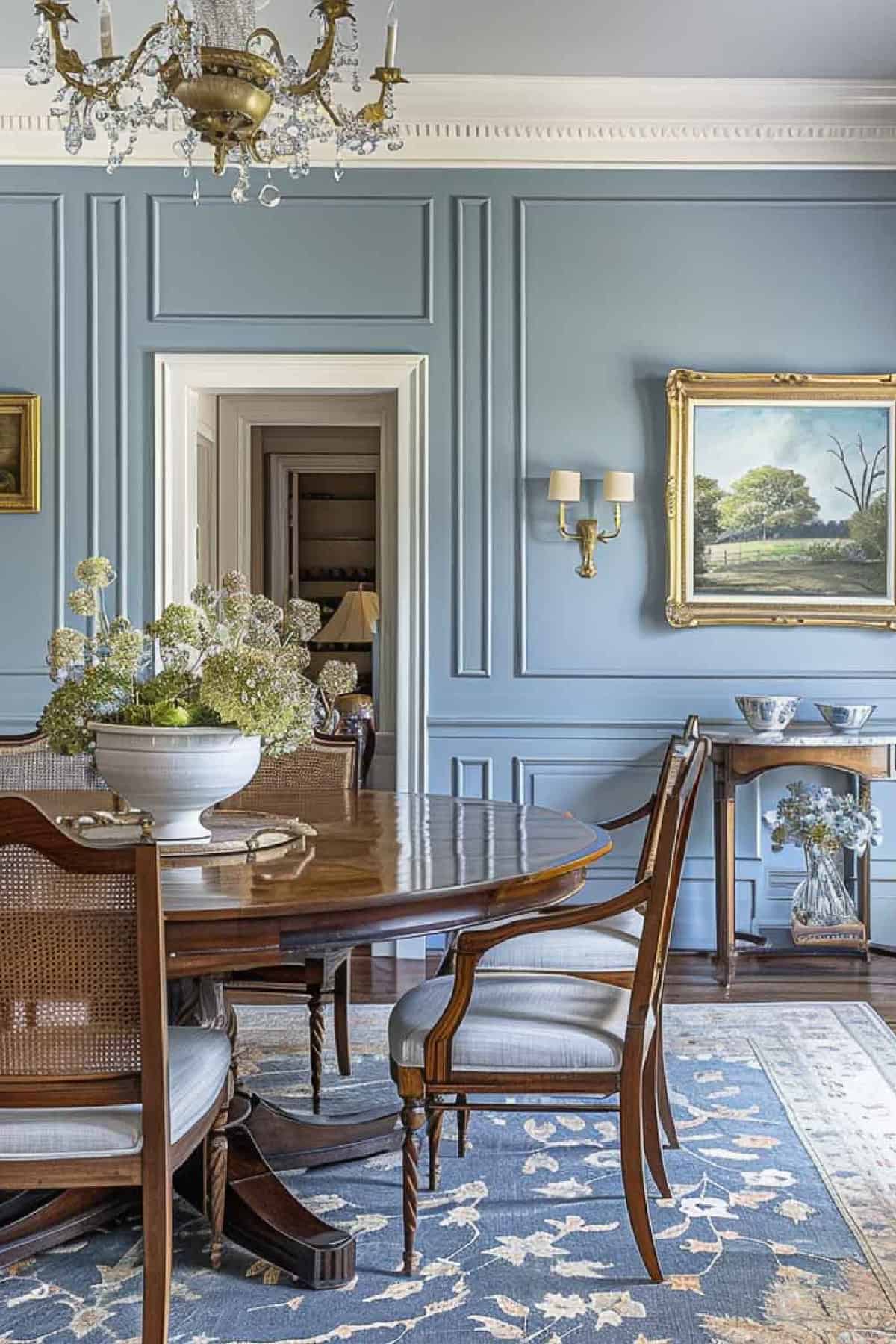 A formal dining room with blue walls and a chandelier.